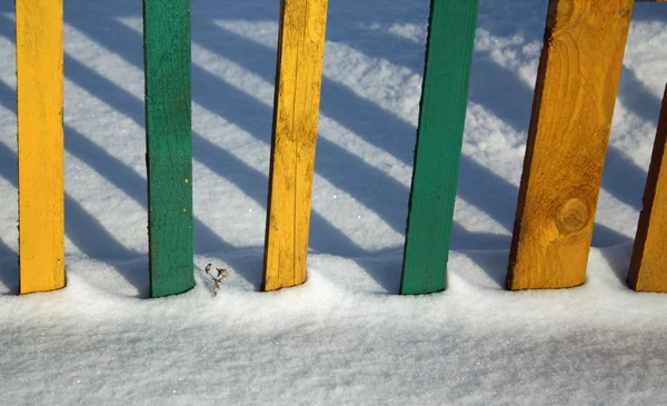 彩色木板栅栏纹理在雪. — 图库照片