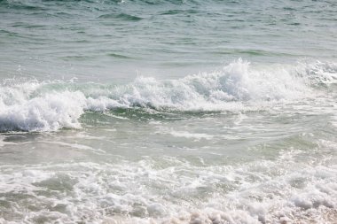 Dalgalar, Alabama 'nın körfez kıyısındaki kumlu kumsalda, parlak güneş ışığı altında süzülüyor..