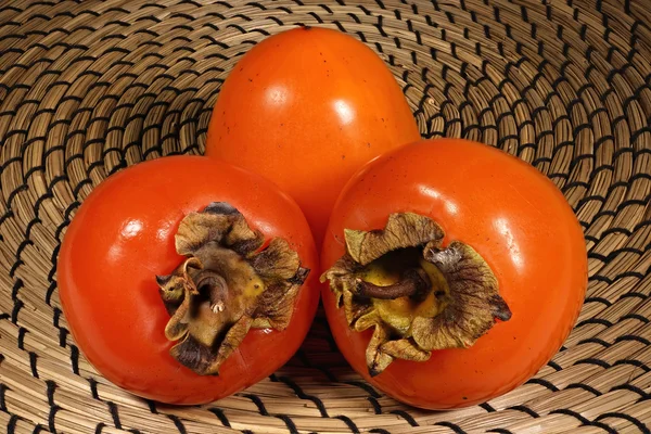 Hasır arka plan üzerinde üç fetal Trabzon hurması 