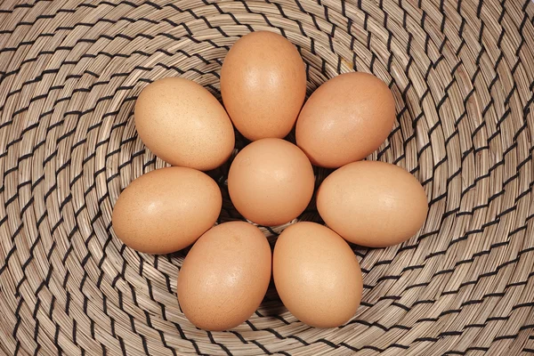 Hasır arka plan üzerinde sekiz tavuk yumurta.