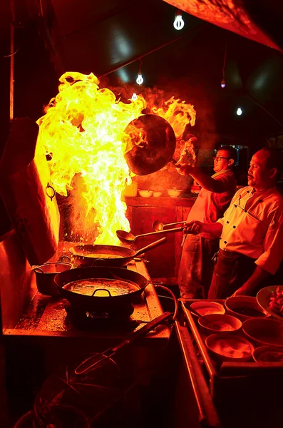 Two chefs are cooking in the kitchen. Normal moment at the seafood restaurant in Kota Kinabalu, Sabah. Cooking with dramatic flame is done to attract the customers. — Stock Photo, Image