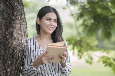 Çekici kadın parkta bir kitap okuma 