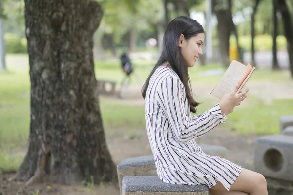 Привлекательная женщина читает книгу в парке — стоковое фото