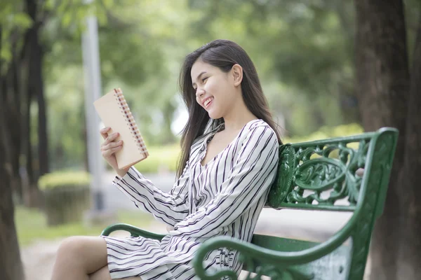 魅力的な女性が公園で本を読んで — ストック写真