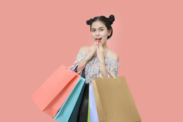 Atractiva mujer compradora sosteniendo bolsas de compras en salmón backgro —  Fotos de Stock