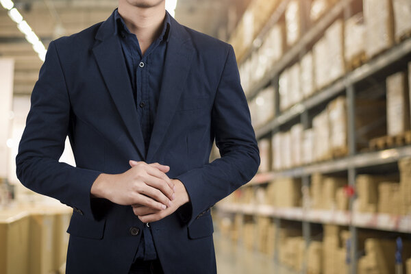  Business man in blue suit standing over warehouse background