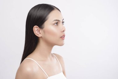 Beyaz arka planda pürüzsüz, sağlıklı bir teni olan genç ve güzel bir kadının portresi.