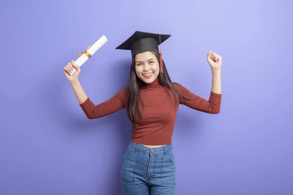 紫罗兰色背景下戴毕业帽的女大学生画像 — 图库照片