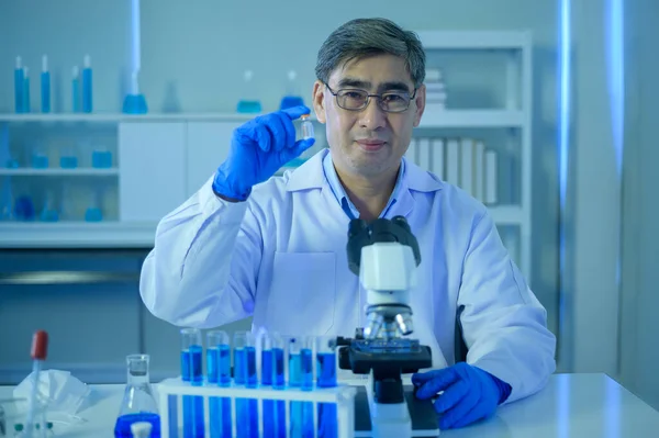 A scientist holding liquid chemical tube in laboratory, Science and technology healthcare concept