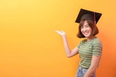 Stüdyo arka planında mezuniyet şapkası takan Asyalı genç bir öğrencinin portresi..