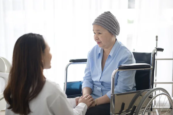 A cancer patient woman wearing head scarf after chemotherapy consulting and visiting doctor in hospital.