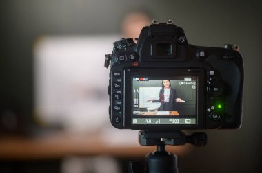 A young woman teacher is using a camera for recording online lesson during quarantine, online education , distance learning concept.	
