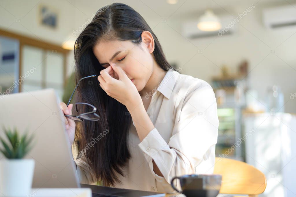 A tired and stressed business woman with headache from using laptop in coffee shop