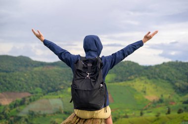 Yağmur mevsiminde, tropikal iklimde, güzel yeşil dağ manzarasının keyfini çıkaran ve rahatlatan gezgin bir adam..