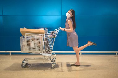 Alışveriş merkezinde tramvayla ameliyat maskesi takan genç bir kadın, covid-19 ve salgın konsepti.