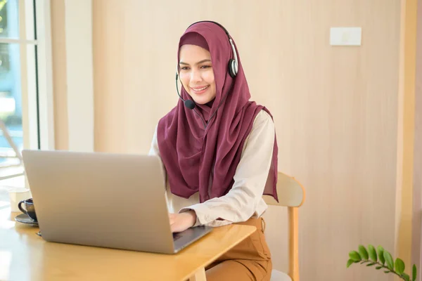 一名穆斯林妇女在耳机中使用计算机接听客户的电话 客户服务的概念 — 图库照片