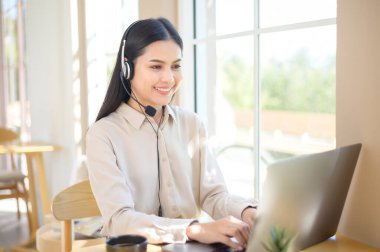 Müşteri hizmetleri operatörü kadın ofiste bilgisayar kullanarak müşteri araması yapıyor.