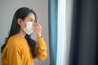 Koruyucu bir maske takan genç ve güzel bir kadın dışarı çıkmaya hazırlanıyor, sağlık sigortası ve Cvid-19.