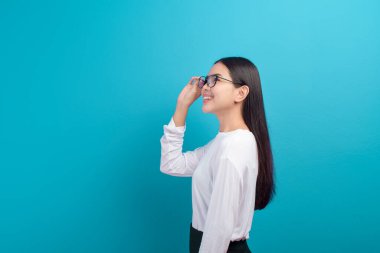 Mavi arka plan stüdyosuna gözlük takan genç bir kadının portresi, sağlık hizmeti konsepti.