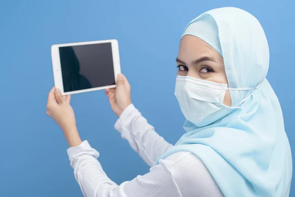 Egy Fiatal Hidzsábos Muszlim Sebészeti Maszkot Visel Táblagéppel Kék Háttér — Stock Fotó