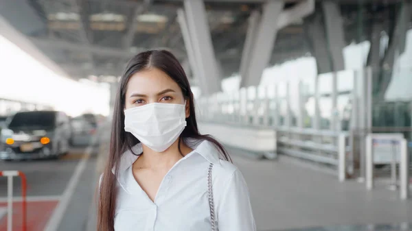 A business woman is wearing protective mask in International airport, travel under Covid-19 pandemic, safety travels, social distancing protocol, New normal travel concept