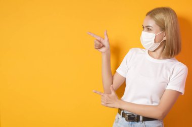 Stüdyoda cerrahi maske takan kısa sarı saçlı bir kadının portresi.