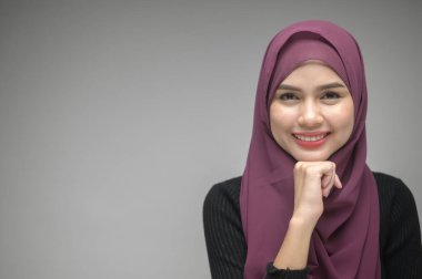 Beyaz arka plan stüdyosunda genç Müslüman bir kadının portresi.