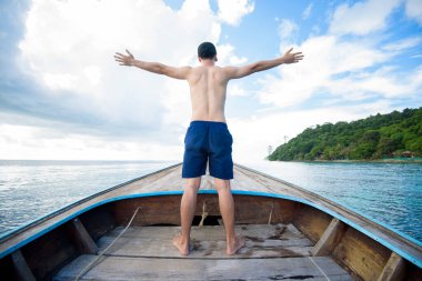 Tayland 'daki Phi phi Adaları' nda Tayland 'da geleneksel uzun kuyruklu teknenin tadını çıkaran mayo giymiş bir adamın görüntüsü.
