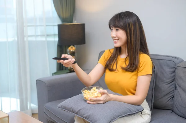 A young happy woman watching movie and relaxing at home