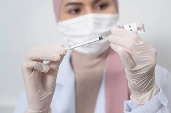 一名年轻的女穆斯林医生拿着注射器 注射器装有Covid 19疫苗瓶 用于注射 Covid 19疫苗和保健概念 — 图库照片