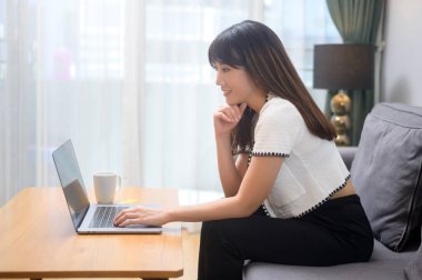 Dizüstü bilgisayarıyla çalışan ve bir fincan kahve içen genç bir kadın, yaşam tarzı ve iş konsepti.