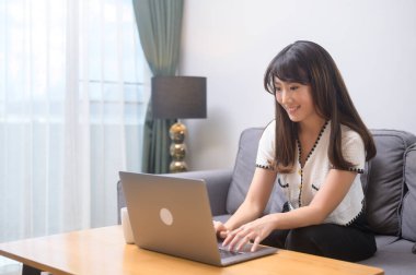 Dizüstü bilgisayarıyla çalışan ve bir fincan kahve içen genç bir kadın, yaşam tarzı ve iş konsepti.