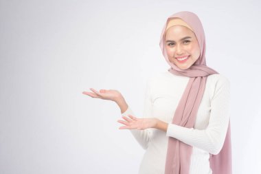 Beyaz arka plan stüdyosuna pembe tesettürlü gülümseyen müslüman bir kadının portresi..