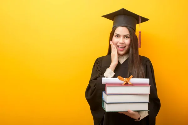 Schöne Frau Abschlusskleid Hält Bücher Und Urkunde Auf Gelbem Hintergrund — Stockfoto