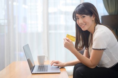 Genç ve güzel bir kadın internet sitesinden alışveriş için kredi kartı kullanıyor. E-ticaret konsepti.