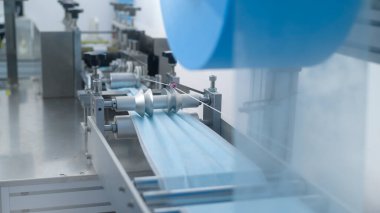 Modern fabrikada cerrahi maske, Covid-19 koruma ve tıbbi konsept üretme makinelerini kapatın..