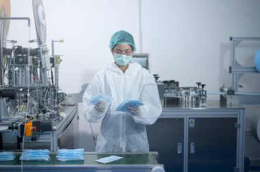 Modern fabrikada cerrahi maske üreten işçiler, Covid-19 koruma ve tıbbi konsept.