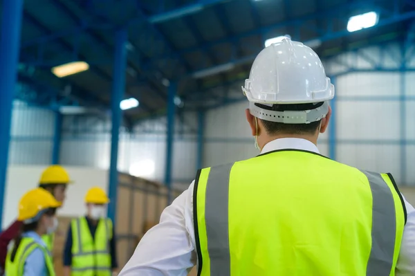 Engineer people are putting a protective helmet on  head in warehouse