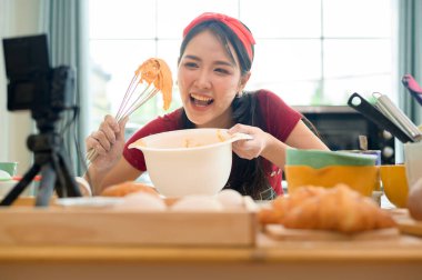 Güzel bir Asyalı kadın evinde fırın yapıyor, canlı yayın yapıyor ya da sosyal medyada video kaydediyor.  