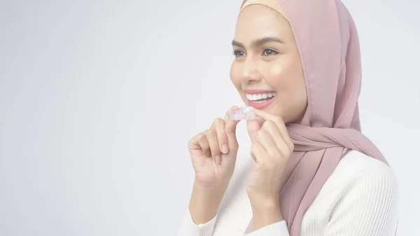 白い背景スタジオ 歯科医療 整形外科の概念上のInvisalignブレースを持っている若いイスラム教徒の女性 — ストック写真