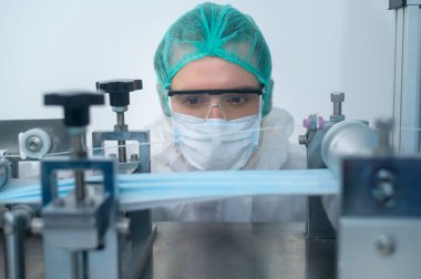 Modern fabrikada cerrahi maske, Covid-19 koruma ve tıbbi konsept üreten işçilere yakın çekim.