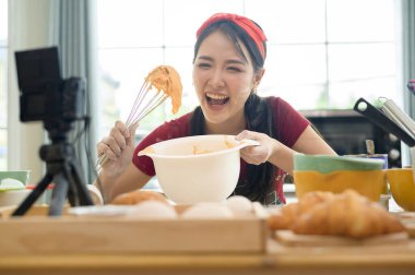 Güzel bir Asyalı kadın evinde fırın yapıyor, canlı yayın yapıyor ya da sosyal medyada video kaydediyor.  