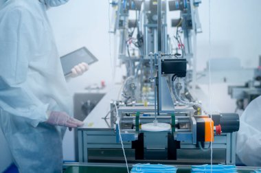 Modern fabrikada cerrahi maske üreten işçiler, Covid-19 koruma ve tıbbi konsept.