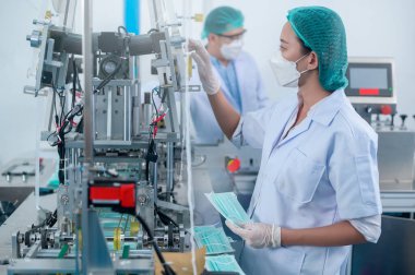 Modern fabrikada cerrahi maske üreten işçiler, Covid-19 koruma ve tıbbi konsept.