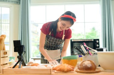 Güzel bir Asyalı kadın evinde fırın yapıyor, canlı yayın yapıyor ya da sosyal medyada video kaydediyor.  