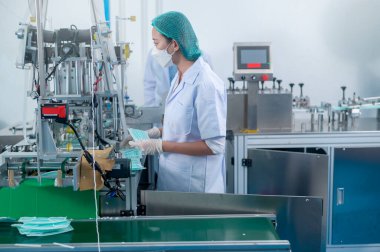 Modern fabrikada cerrahi maske üreten işçiler, Covid-19 koruma ve tıbbi konsept.