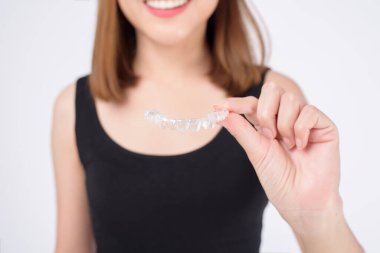 Stüdyoda diş sağlığı hizmetleri ve ortodontik konseptte diş teli tutan gülümseyen genç bir kadın.