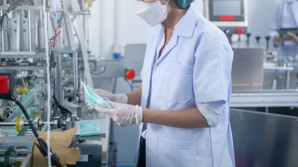 Modern fabrikada cerrahi maske üreten işçiler, Covid-19 koruma ve tıbbi konsept.