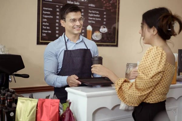 Baristas hand taking cup of hot coffee and bakery to offering to customer  in coffee shop