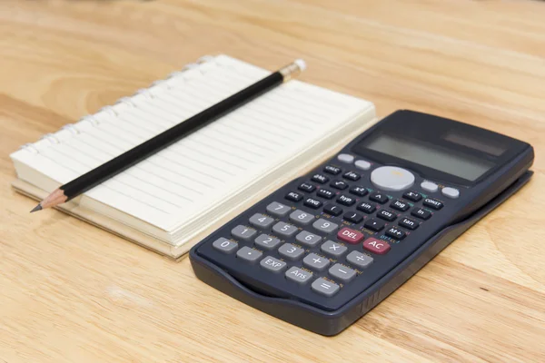 Калькулятор, нотатка та олівець на фоні дерева — стокове фото